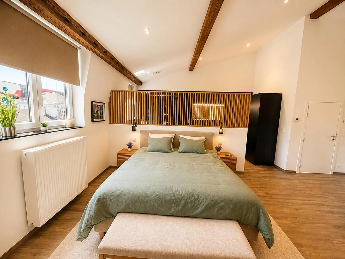 Die Suite: salbeigrünes Kingsize-Bett unter den Balken, Kopfteil aus Holz