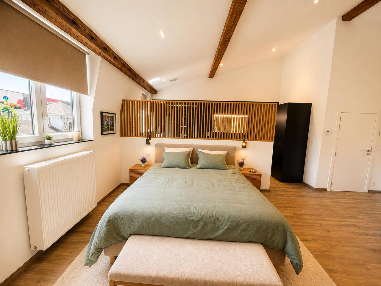 La suite : lit king-size vert sauge sous les poutres, tête de lit en bois