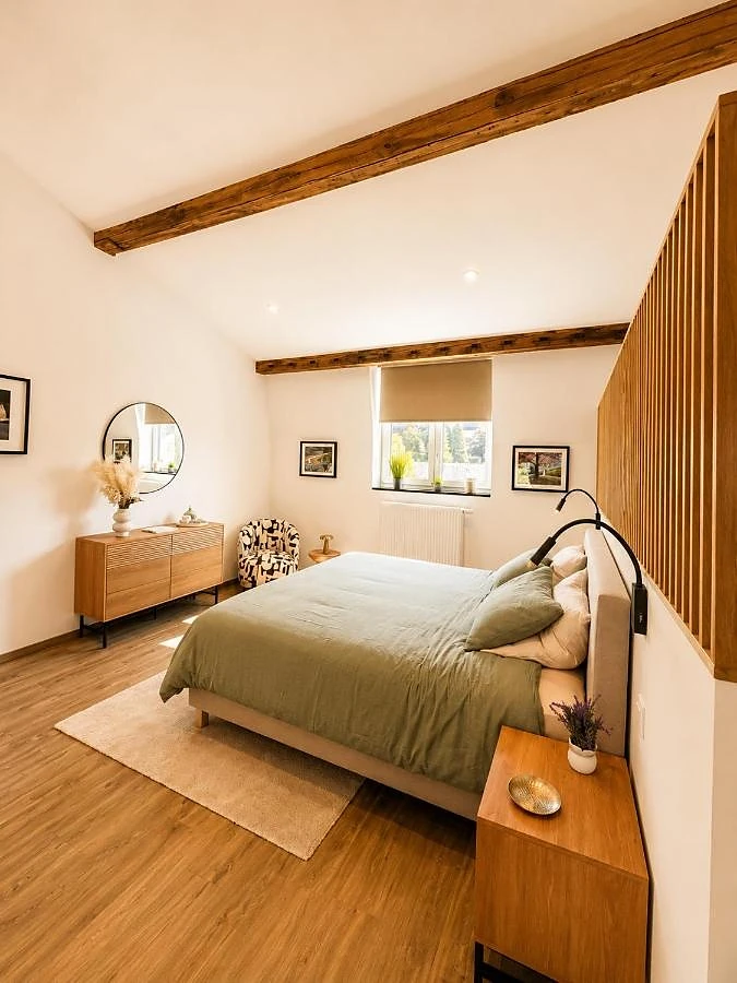 Das Schlafzimmer: salbeigrünes Bett, Kommode und runder Spiegel