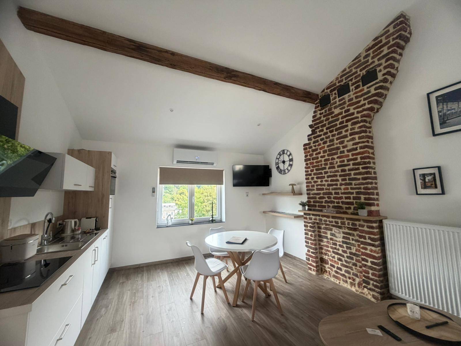 Coin repas et cuisine équipée avec mur en brique